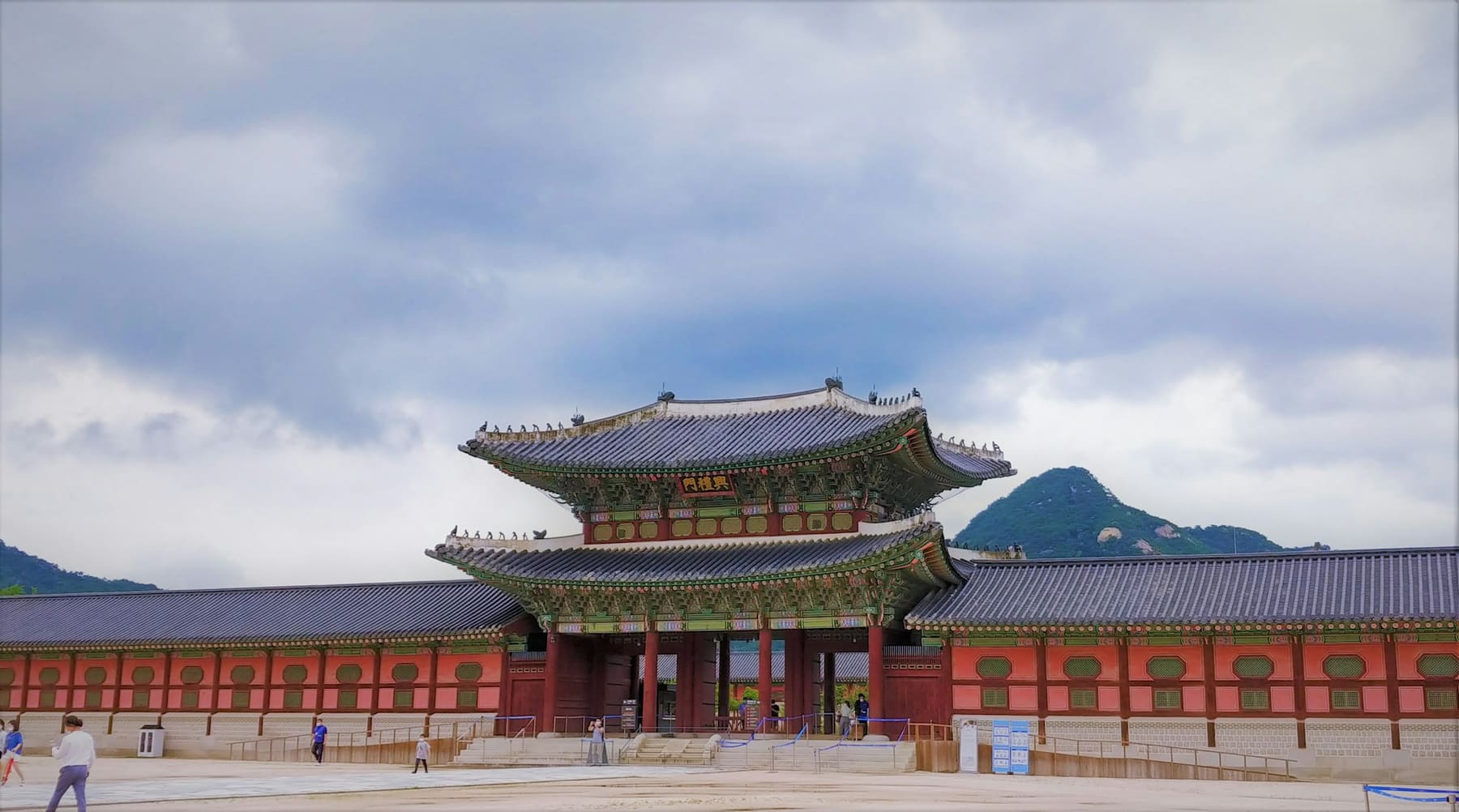 A two-storey gate pavilion at Gyeongbokgung Palace in Seoul, with a mountain behind