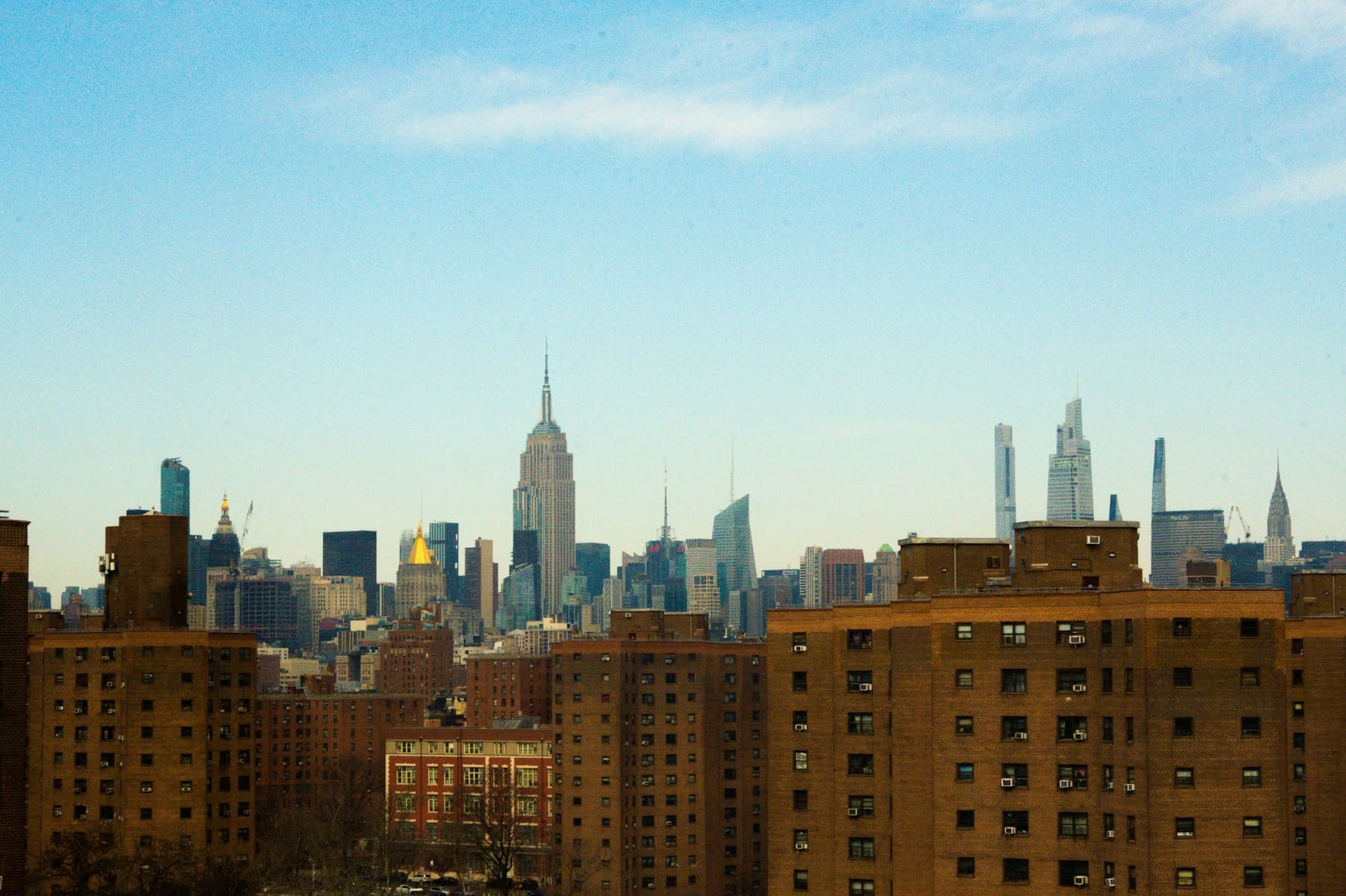 The Manhattan skyline with the Empire State Building, behind brick apartment blocks in New York City
